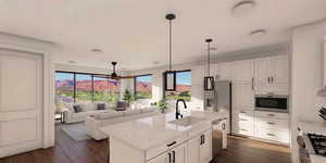 Kitchen featuring dark wood-style flooring, light stone counters, open floor plan, and a center island with sink