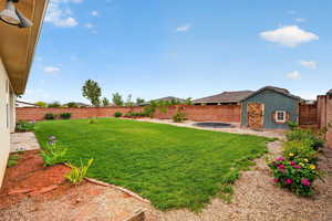 Fenced backyard featuring an outbuilding and a patio area