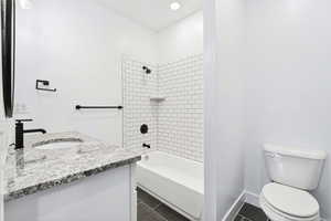 Full bath featuring vanity, dark tile patterned floors, shower / tub combination, and recessed lighting