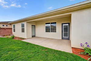 Rear view of property featuring stucco siding, a yard, and a covered patio