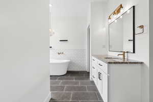 Bathroom with vanity, tile walls, a freestanding bath, and wainscoting