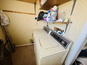 Laundry area with wallpapered walls and independent washer and dryer