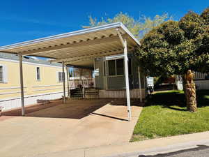 View of front of house featuring a front lawn, a wooden deck, a carport, and concrete driveway