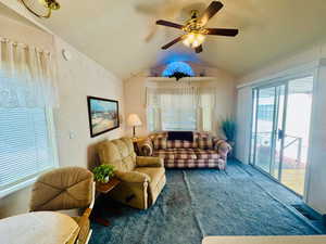 Carpeted living area featuring ceiling fan and a textured ceiling