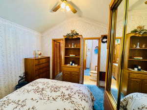 Bedroom with a closet, wallpapered walls, a textured ceiling, ceiling fan, and dark colored carpet
