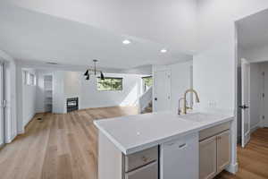 Kitchen with white dishwasher, a fireplace, light wood-style floors, recessed lighting, and open floor plan