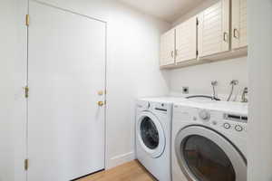 Laundry room featuring cabinet space, light wood-style flooring, and washer and dryer