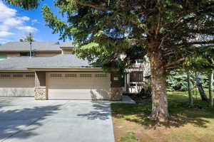 View of front of house featuring roof with shingles, stone siding, driveway, a garage, and a front yard