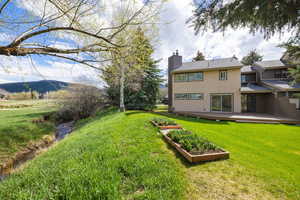Rear view of property with a lawn, a chimney, and a garden