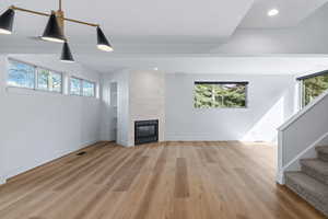 Unfurnished living room with recessed lighting, light wood finished floors, and a tile fireplace