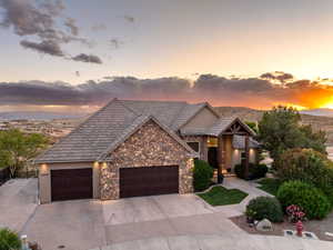 Craftsman house featuring stone siding, an attached garage, driveway, and stucco siding