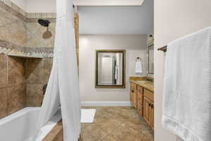 Full bathroom with tiled shower / bath, double vanity, and light tile patterned floors