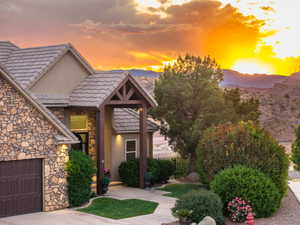 View of front of house featuring stone siding, stucco siding, an attached garage, and driveway