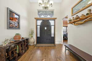 Entryway featuring hardwood / wood-style floors, a chandelier, and a high ceiling