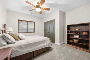 Bedroom with light carpet, ceiling fan, and a closet