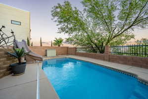 Pool at dusk with a water slide, a fenced backyard, and a patio
