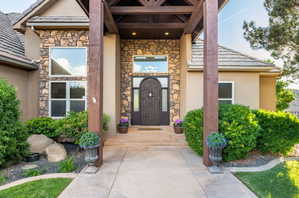 Doorway to property with stone siding, stucco siding, and a tile roof