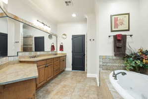 Bathroom with a whirlpool tub, double vanity, light tile patterned flooring, and recessed lighting
