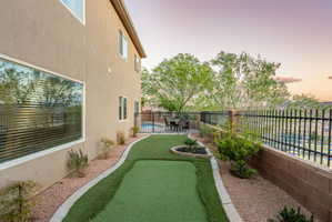 Yard at dusk with a fenced backyard, a putting area, and a patio area