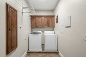Laundry room with independent washer and dryer, cabinet space, electric panel, and light tile patterned flooring