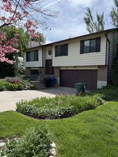 Bi-level home with brick siding, a garage, driveway, and a front yard