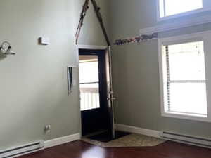Spare room featuring baseboard heating, dark wood finished floors, and a high ceiling
