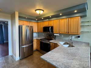Kitchen featuring stainless steel appliances, light wood-finish cabinetry, granite-style countertops, an undermount sink, and recessed lighting