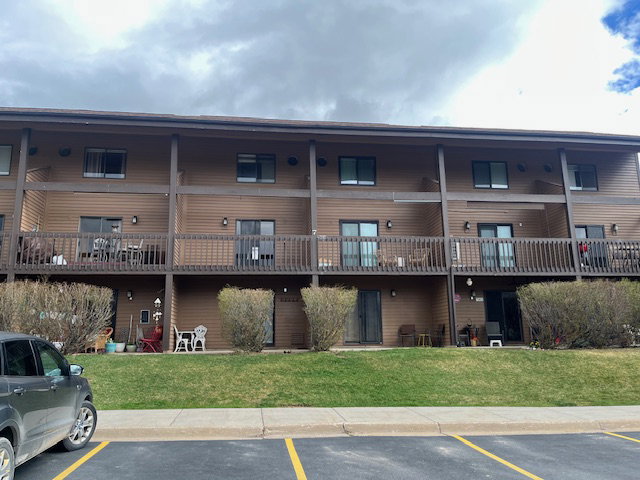 View of apartment building / complex featuring uncovered parking