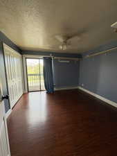 Spacious room featuring wood-finish flooring, a ceiling fan, and sliding glass doors leading to a private balcony