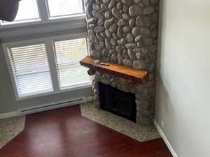 Unfurnished living room featuring a fireplace, a textured ceiling, a baseboard radiator, and dark wood-style flooring