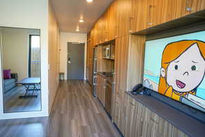 Kitchen featuring dark countertops, wood finish cabinetry, dark wood-style flooring, stainless steel appliances, and modern cabinets