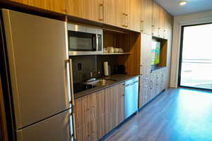 Kitchen with stainless steel appliances, dark wood finished floors, open shelves, modern cabinets, and light wood finish cabinets