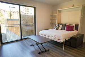 Bedroom featuring access to exterior and dark wood-style flooring