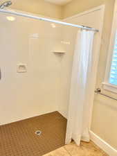 Full bath featuring a shower stall and light tile patterned flooring