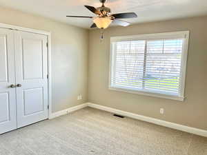 Unfurnished bedroom featuring light carpet, a closet, and ceiling fan