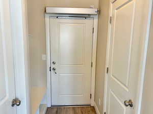 Doorway to outside with wood finished floors and baseboards