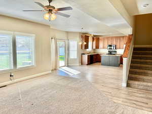 Kitchen with open floor plan, light countertops, black appliances, ceiling fan, and decorative light fixtures