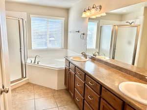 Bathroom featuring double vanity, a garden tub, a stall shower, and light tile patterned flooring