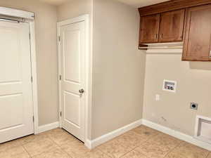 Laundry area featuring hookup for a washing machine, light tile patterned floors, cabinet space, and hookup for an electric dryer
