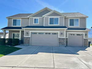 Craftsman-style house featuring stone siding, an attached garage, concrete driveway, and covered porch