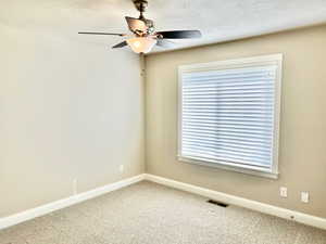 Unfurnished room featuring a textured ceiling, a ceiling fan, and light colored carpet