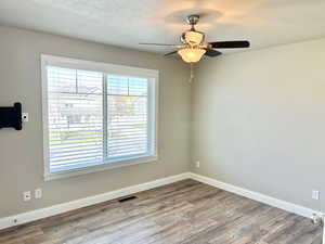 Empty room featuring wood finished floors, a ceiling fan, and a textured ceiling