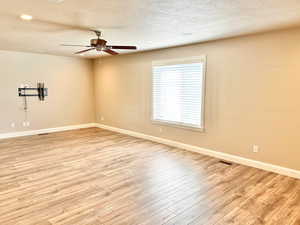 Empty room featuring light wood-style floors, a textured ceiling, ceiling fan, and recessed lighting