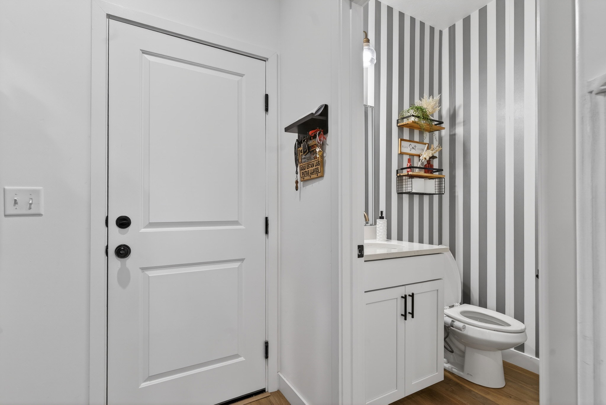 Bathroom featuring vanity, wallpapered walls, and dark wood-type flooring