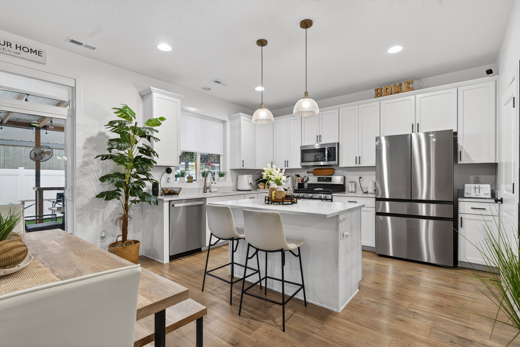 Kitchen with stainless steel appliances, a center island, light wood-style flooring, a kitchen bar, and white cabinets