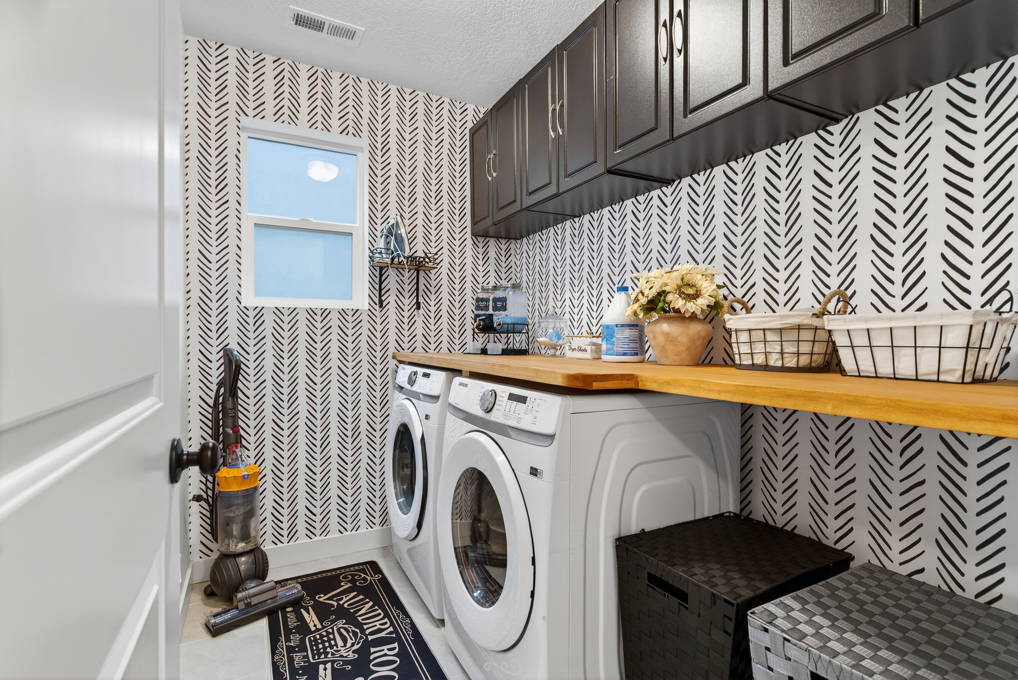 Laundry room with cabinet space, wallpapered walls, a textured ceiling, and washing machine and dryer