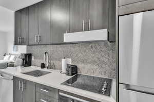 Kitchen with stainless steel appliances, light stone countertops, decorative backsplash, modern cabinets, and extractor fan