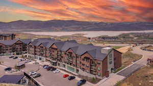 Aerial view at dusk of a water and mountain view and a view of apartment building / complex