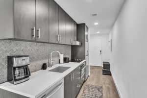 Kitchen with dishwasher, modern cabinets, light stone countertops, light wood-type flooring, and recessed lighting