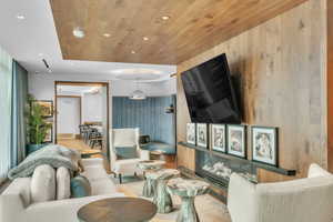 Living room with recessed lighting, wood ceiling, wood walls, a glass covered fireplace, and wood finished floors